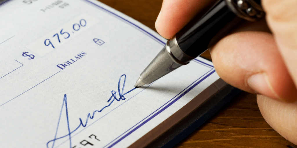 A close-up shot of a check being signed, representing a bad or worthless check