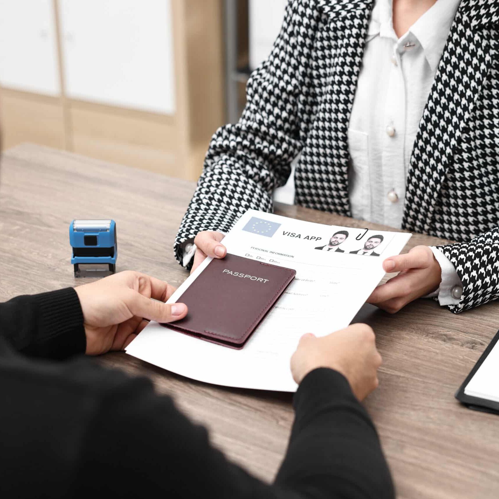 Immigration to European Union. Embassy worker giving visa application form and passport to man in office, closeup Immigration to European Union. Embassy worker giving visa application form and passport to man in office, closeup
